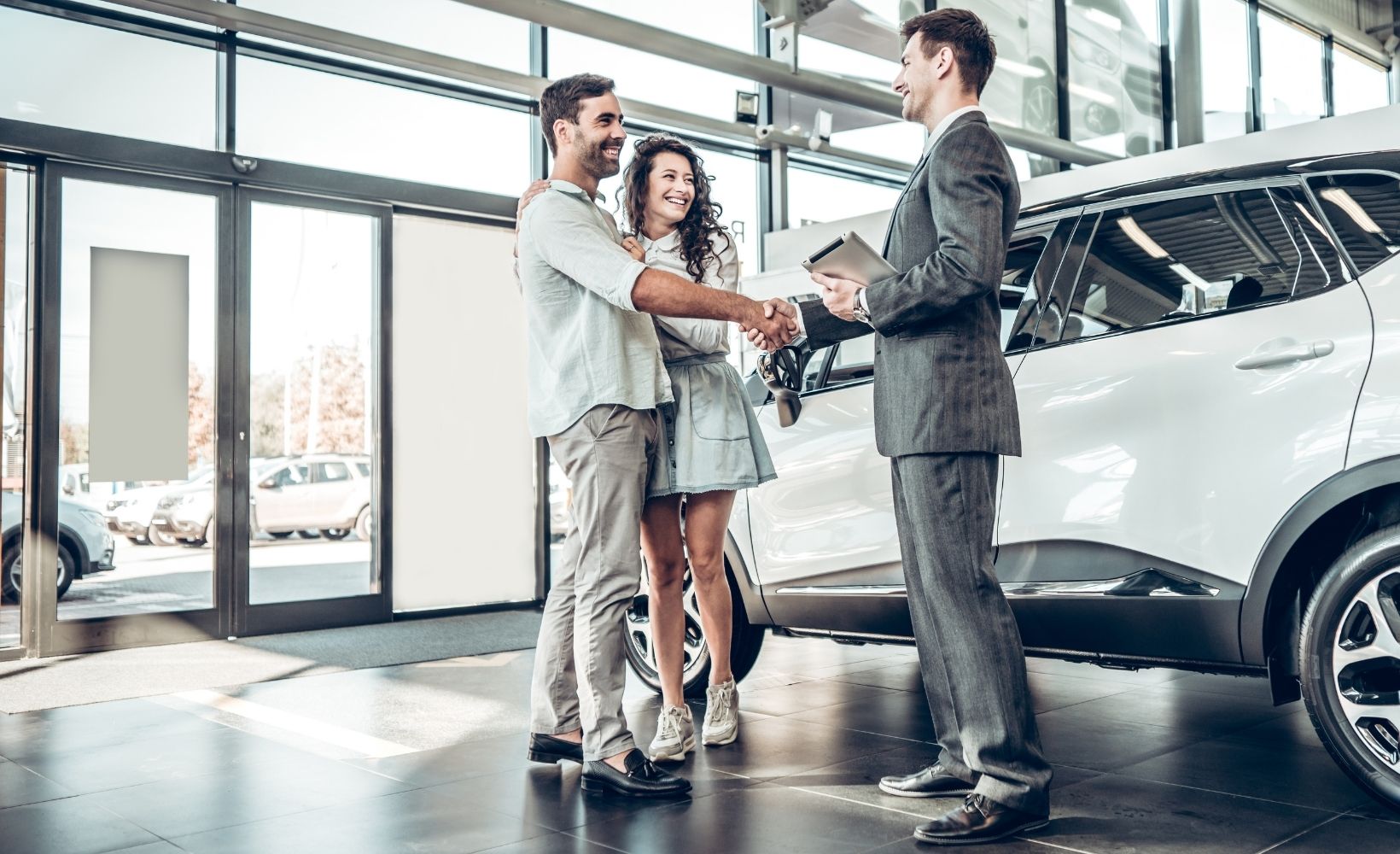 Eine erfolgreiche Übergabe eines neuen Autos an ein paar Pärchen durch einen Automobilkaufmann.