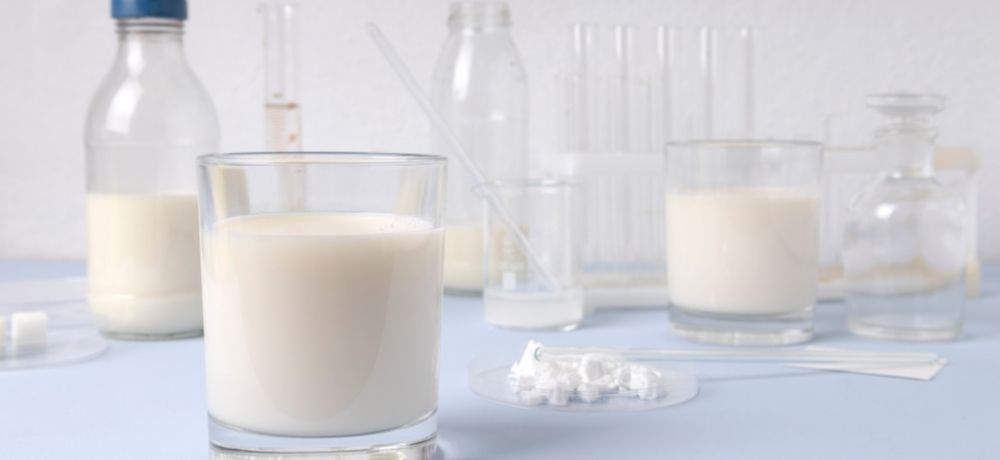 Verschiedene Gläser gefüllt mit Milch und verschiedenen wissenschaftlichen Werkzeugen wie Pipetten und mehr.