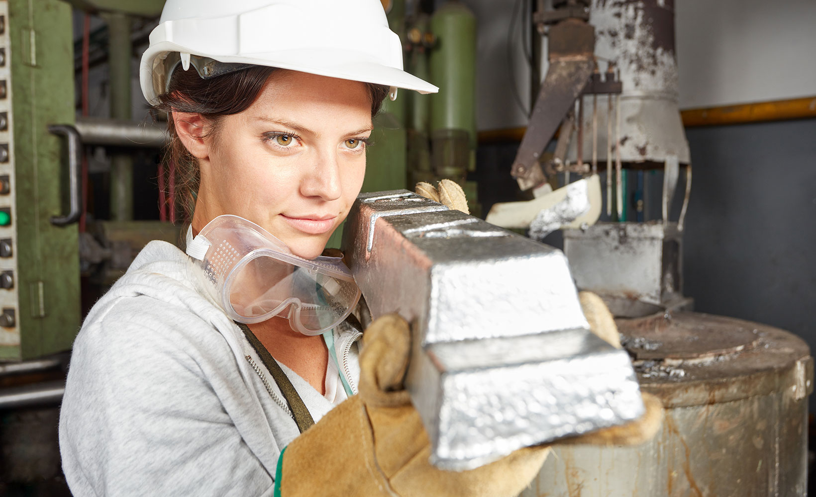 Eine Verfahrenstechnologin hält eine Metallblock in der Hand und betrachtet diesen gründlich.