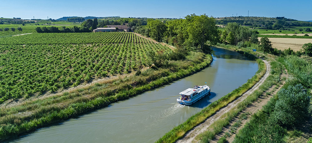 Eine Landschaft mit einem Fluss auf dem ein Boot fährt.