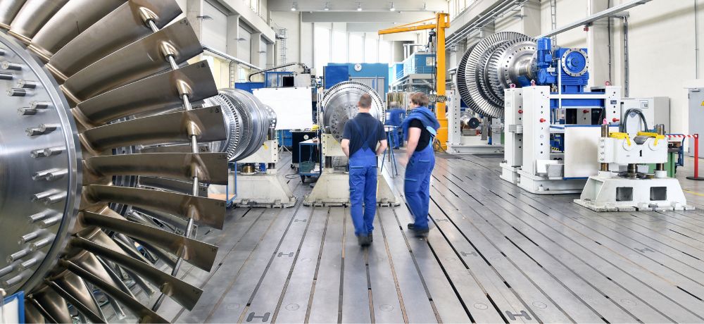 Elektroniker und Elektronikerin laufen durch die Produktionshalle.