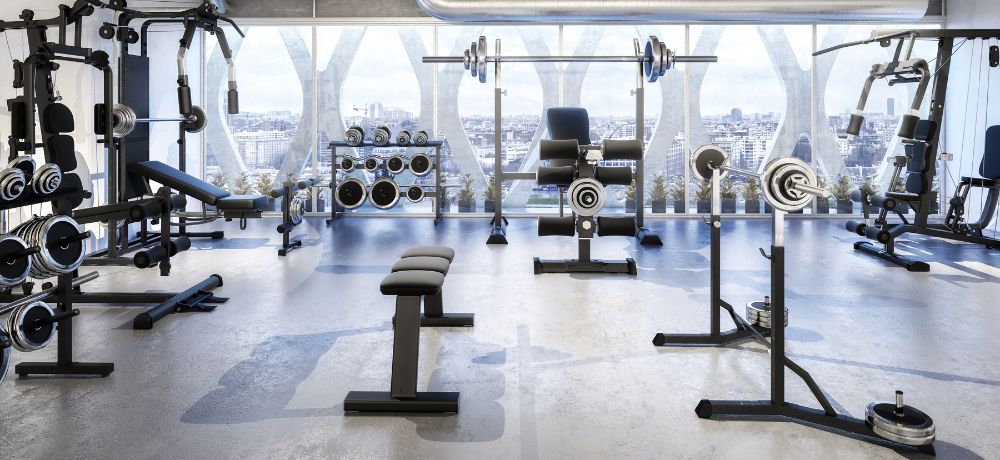 Ein Fitnessstudio in schlichter Farbe und mit einer großen Fensterwand für eine schöne Aussicht.