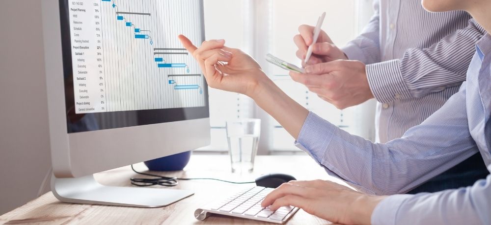 Mitarbeiter*innen der Controlling Abteilung überprüfen ein Organigramm im Projektmanagement.
