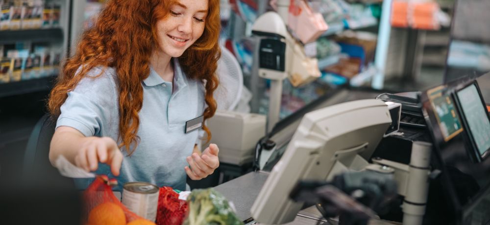 Junge Frau kassiert im Supermarkt Lebensmittel ab
