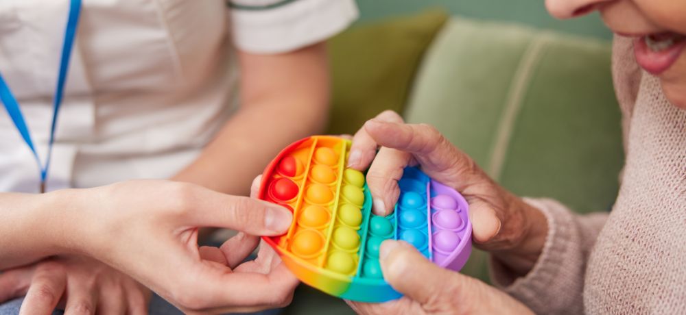 Ergotherapeutin macht eine Übung für die Finger mit einer Dame.