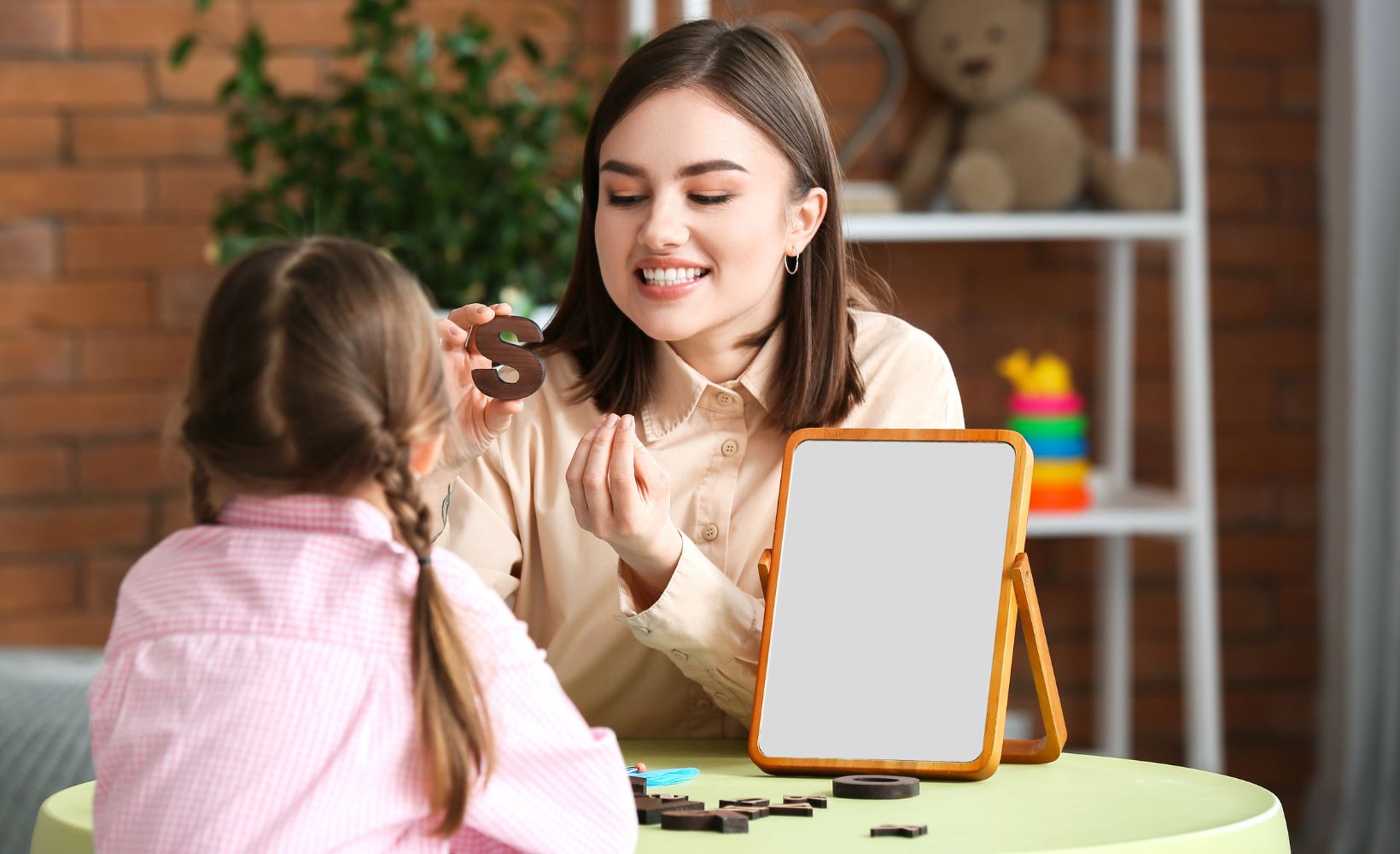 Logopaedin macht mit Mädchen Sprechübungen zum Buchstaben S.