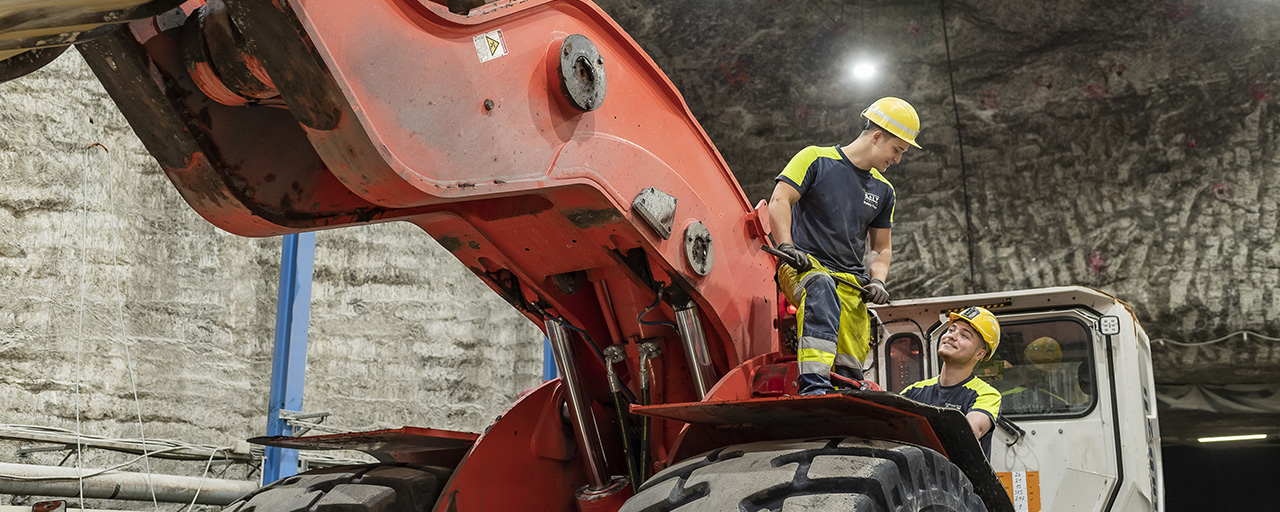 Zwei Mitarbeiter arbeiten mit einem Bagger im Salzwerk.