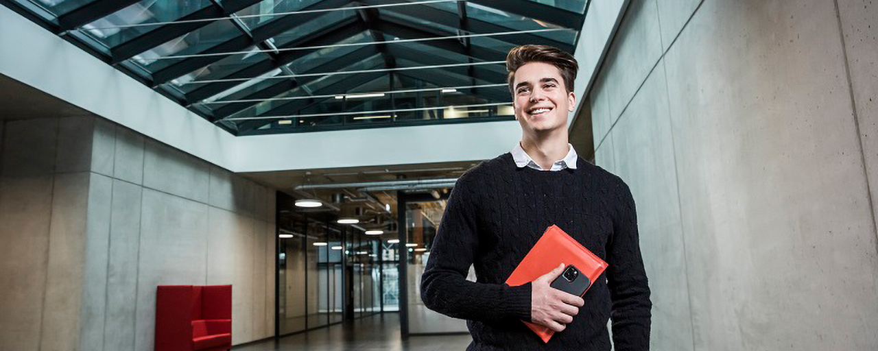 Ein junger Mann hält ein rotes Etui und ein Smartphone in der Hand.