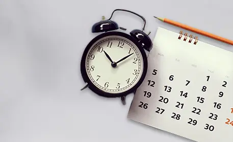 Wecker mit Kalender im Hintergrund