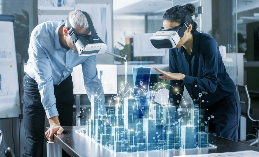 Zwei Kollegen eines Berufs mit VR-Brillen über einer 3-D-Gebäudedarstellung.