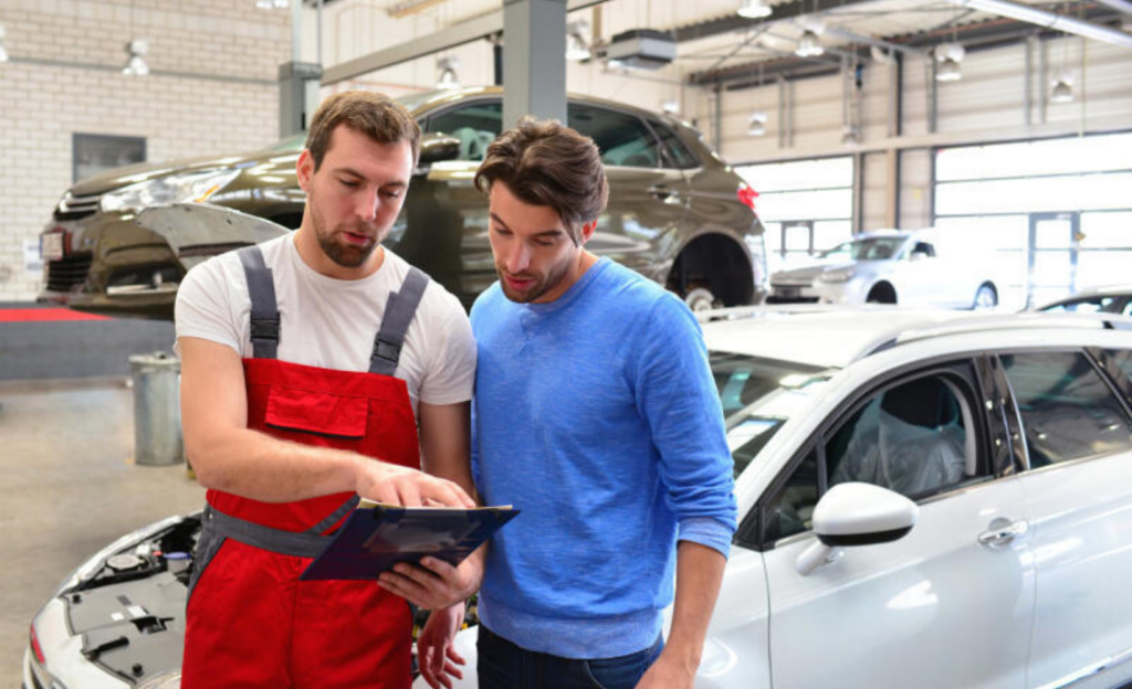 Zwei Kfz-Mechatroniker diskutieren in der Werkstatt einen Auftrag.