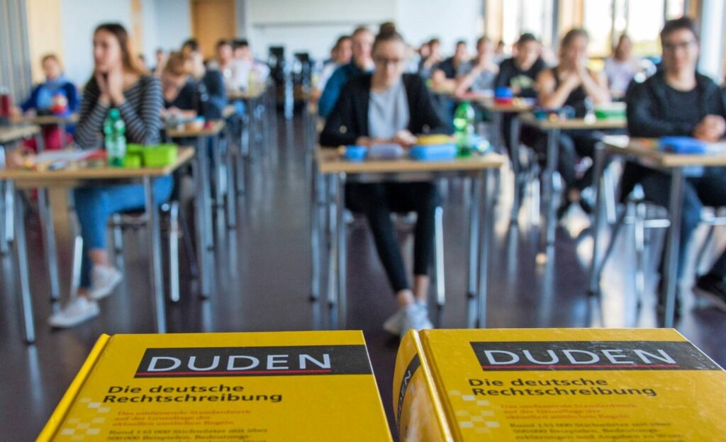 Bei einer Prüfung zum Abitur liegen zwei gebundene Duden vor der Abschlussklasse.