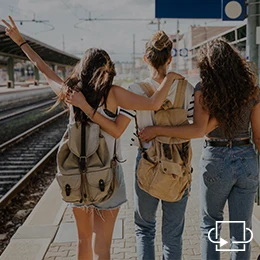 Drei junge Frauen stehen am Bahnhof