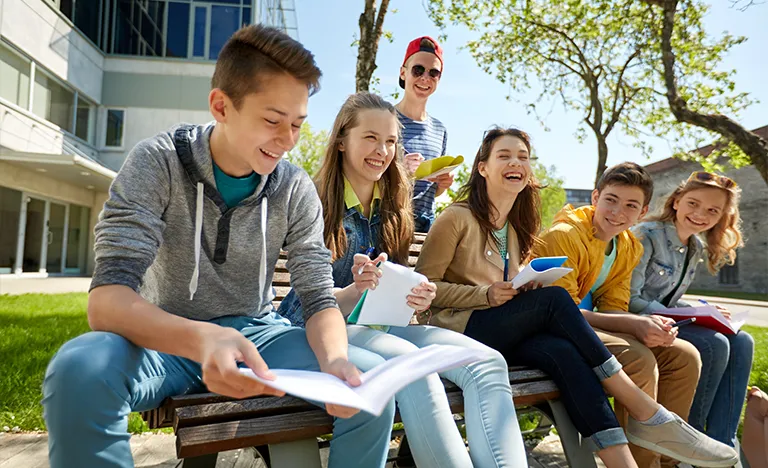 Sprachreisen oder Schuljahr im Ausland: Eine Gruppe von Schülern sitzt im Freien und schreibt in Hefte