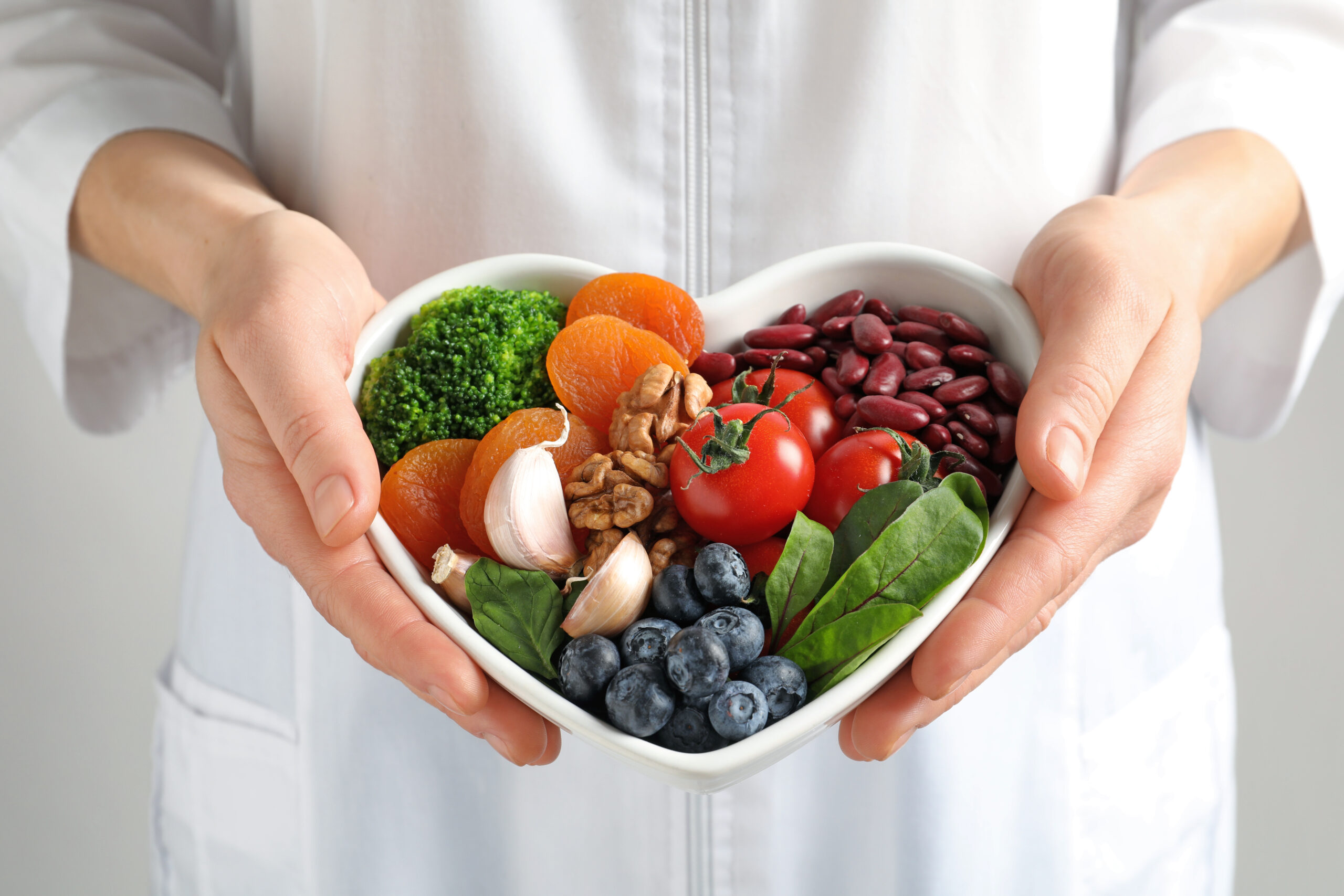 Doctor holding bowl with products for heart-healthy diet, closeup