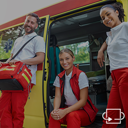 Gruppe von drei Sanitätern, die lächelnd vor dem Krankenwagen stehen.