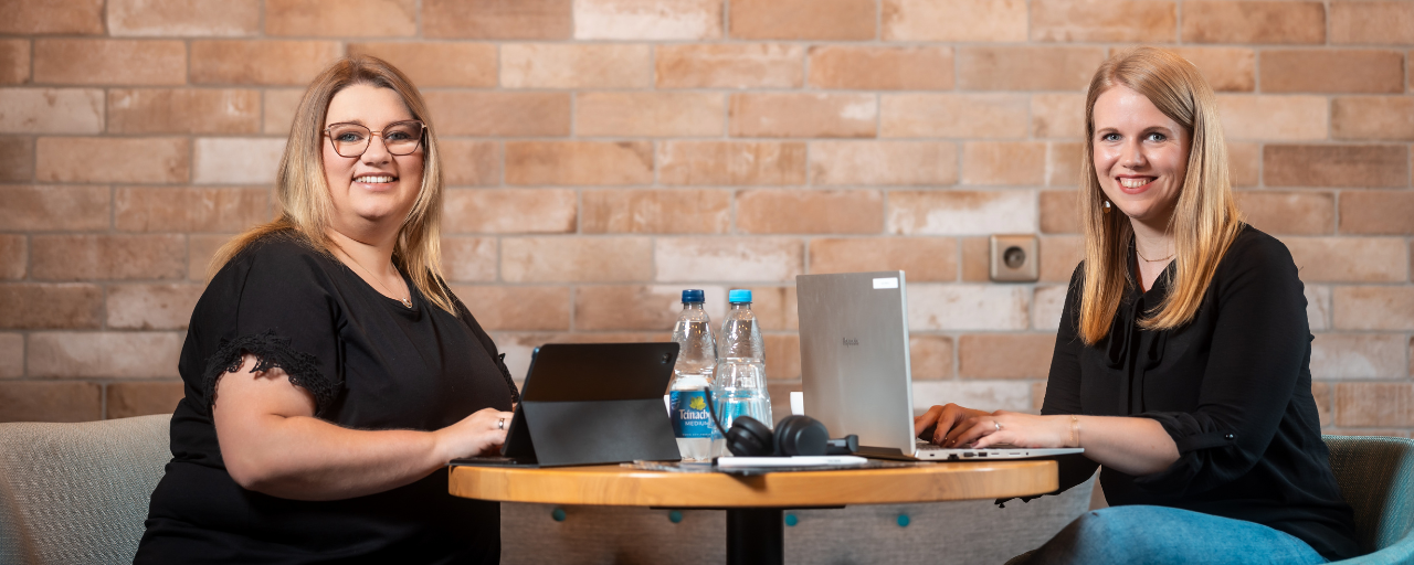 Zwei Mitarbeiterinnen arbeiten digital an Laptop und iPad.