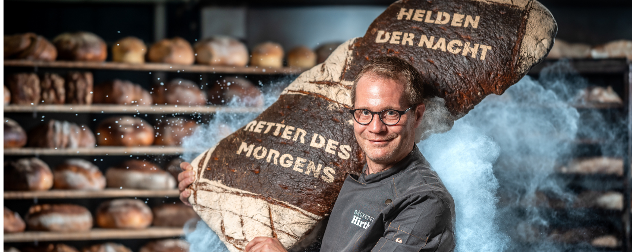 Mitarbeiter trägt großes Brot auf den Schultern.