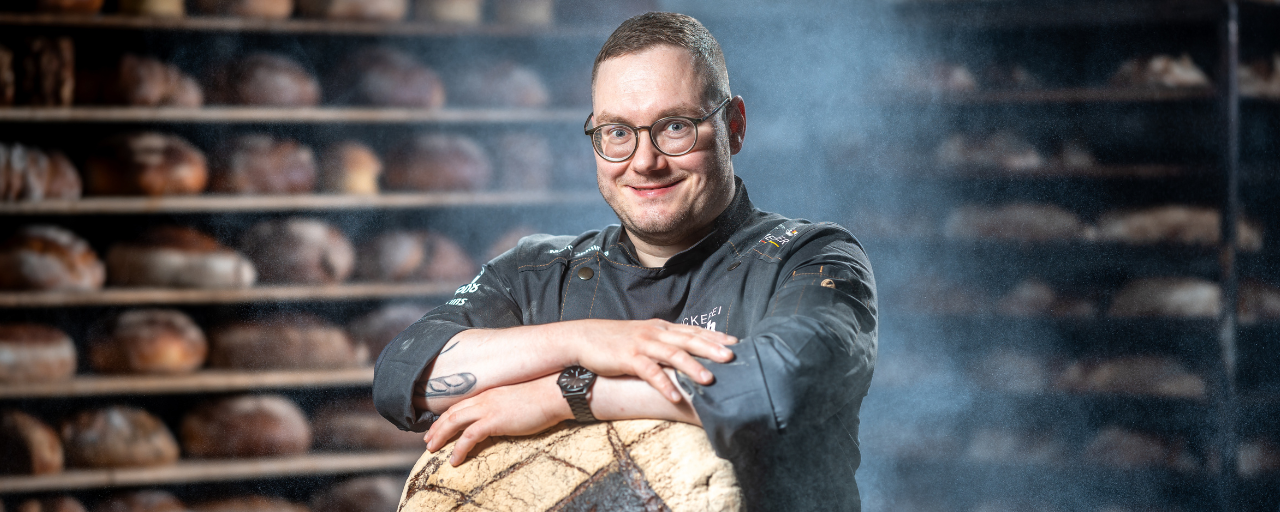 Mitarbeiter lehnt sich auf das ein großes Brot.